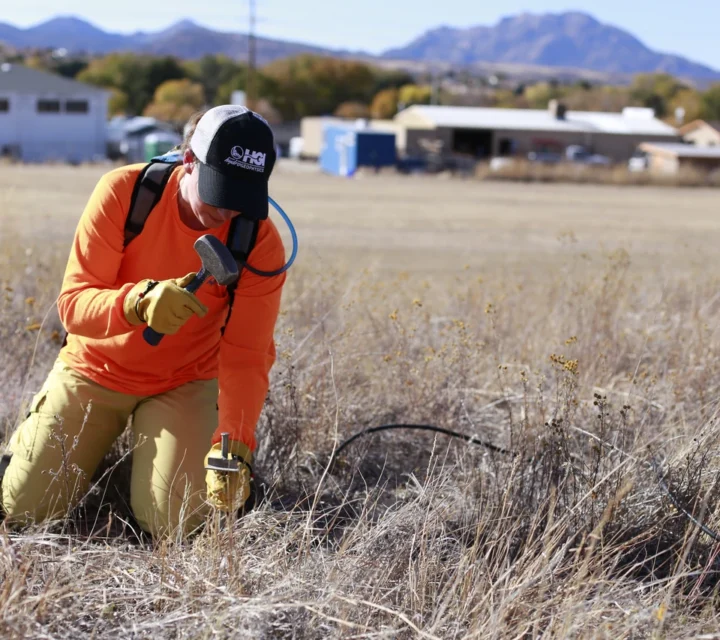 Field technician installing electrodes for 3D electrical resistivity survey to map subsurface geology, fluid pathways, and material variability across site using multi-electrode layout and geophysical data acquisition equipment.
