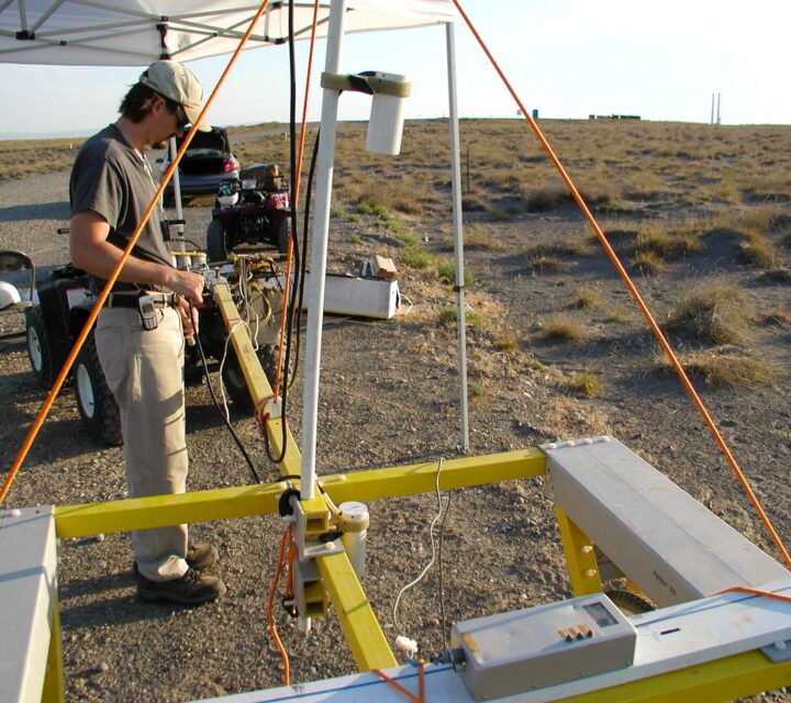 Person operating a large yellow contraption with cables and equipment in a desert setting.