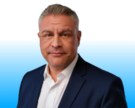 Portrait of a man in a navy suit and white shirt against a blue gradient background.