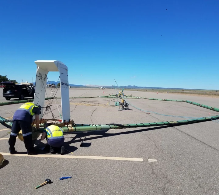 Crew assembling airborne electromagnetic method transmitter loop on runway prior to AEM subsurface survey.