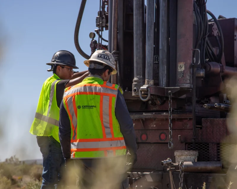 Workers in safety gear operating heavy machinery at a construction site.