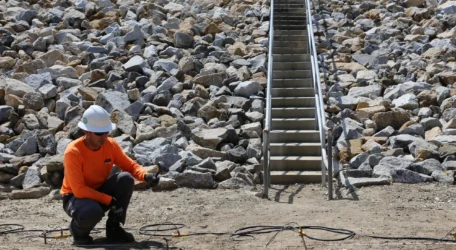 Technician conducting dam leak detection survey along an embankment to evaluate seepage pathways and assess structural integrity using geophysical methods.