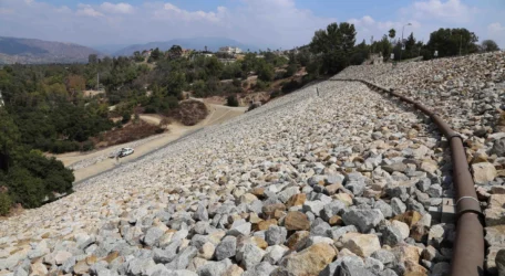 Riprap-covered dam slope monitored during Dam non-invasive monitoring, using geophysical methods to track internal moisture changes, seepage conditions, and structural performance without disturbing the dam structure.