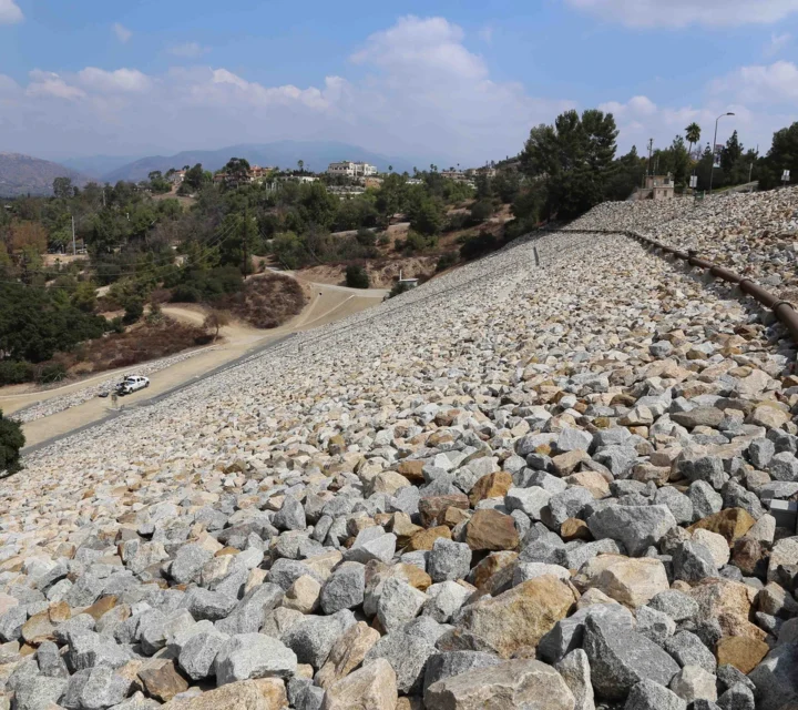 Riprap-covered dam slope monitored during Dam non-invasive monitoring, using geophysical methods to track internal moisture changes, seepage conditions, and structural performance without disturbing the dam structure.