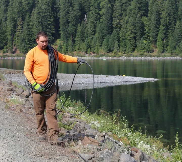 Technician deploys geophysical survey line along dam crest during Dam seepage mapping, collecting subsurface data to identify elevated moisture zones, seepage pathways, and conditions affecting dam integrity and performance.
