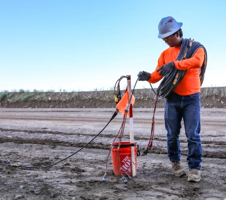 Field technician deploying cables and electrodes for fracture mapping survey to identify subsurface fractures, structural discontinuities, and fluid pathways using non-invasive geophysical methods.