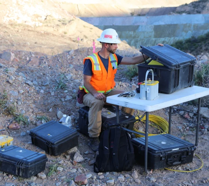 Technician prepares geophysical mapping equipment on mining site, measuring subsurface property contrasts, saturation variations, and structural patterns within engineered materials to support investigation, planning, and interpretation of complex internal conditions.