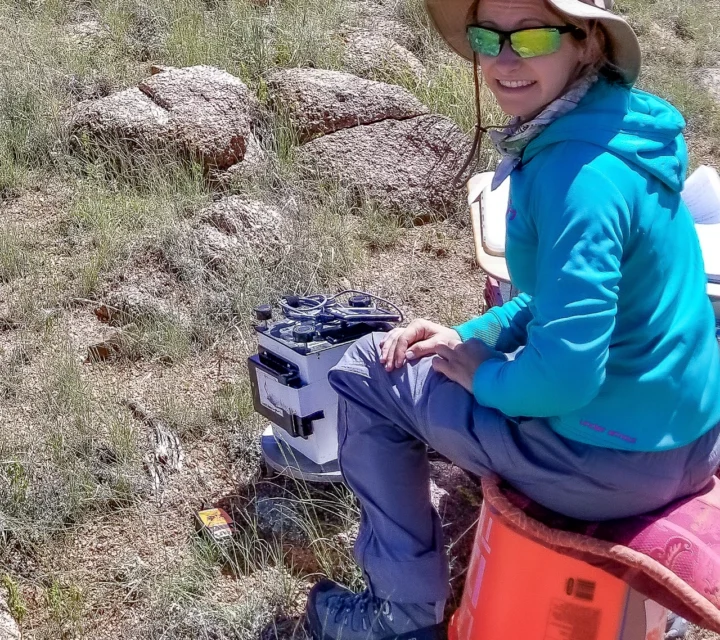 Technician collecting surface readings during gravity surveys using sensitive gravimeter equipment to measure subtle gravitational acceleration changes and identify subsurface density contrasts across a mapped survey area.