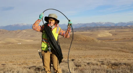 Field technician evaluating streambank conditions during groundwater exploration survey to assess surface water interaction, subsurface flow pathways, and hydrogeologic features influencing groundwater occurrence and movement.