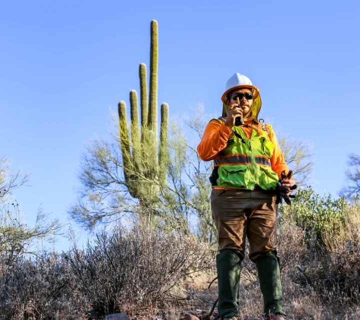 Technician deploying surface geophysical cable during groundwater exploration survey to evaluate subsurface saturation contrasts, basin geometry, structural features, and bedrock boundaries influencing groundwater occurrence and movement.