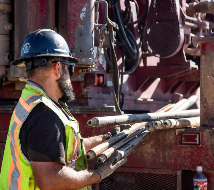 Construction worker handling metal pipes at a work site.