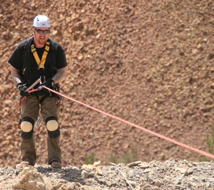 Field technician manages survey line during Heap leach characterization, supporting geophysical imaging of resistivity variations, moisture distribution, and internal flow pathways within engineered rock piles to evaluate permeability contrasts and material heterogeneity.