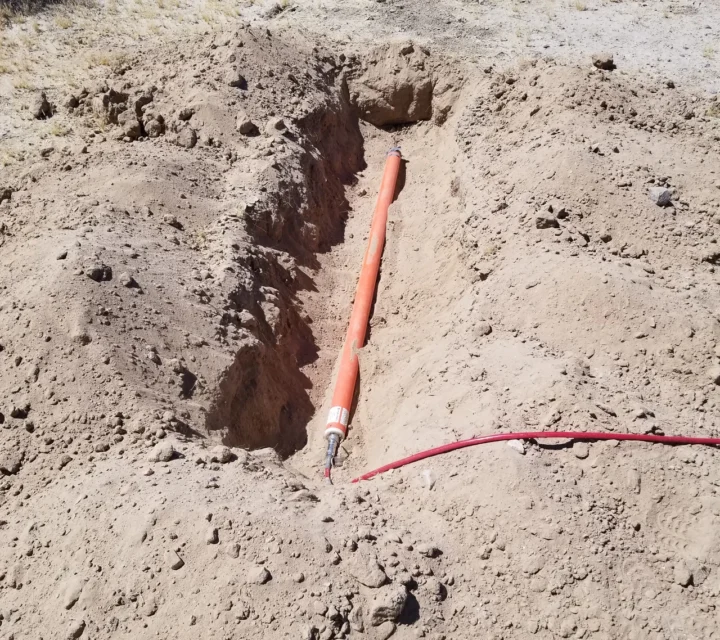 Technician deploying electrodes and magnetic sensors across desert terrain for magnetotellurics survey measuring natural electromagnetic fields to recover subsurface resistivity and image deep basin structure and lithology.