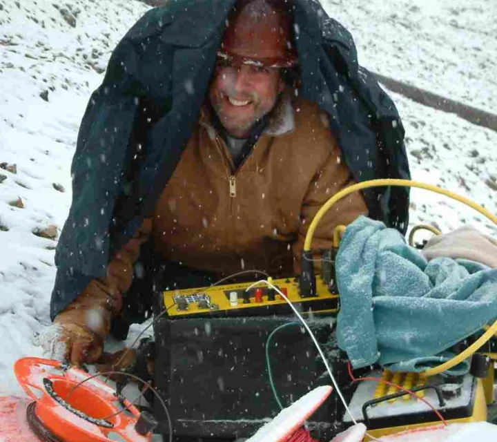 Technician operates geophysical equipment in winter conditions during Mineral exploration, collecting subsurface data and refining models that define target geometry, guide drilling, and support feasibility evaluation.