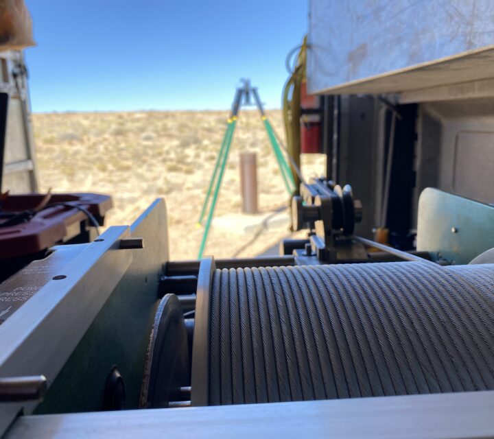 Winch system in a field setting with cables extended towards a tripod in the distance.