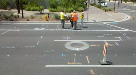 Construction workers discussing road markings on a city street.