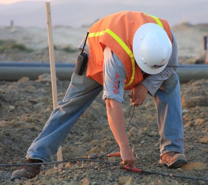Technician installing surface electrodes for plume mapping survey to delineate subsurface contamination, collecting electrical data to define plume boundaries and support groundwater protection and environmental remediation planning.