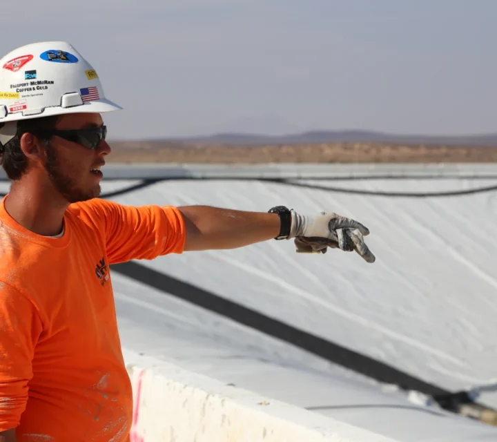Geophysicist reviewing pond leak detection results at a lined containment pond to verify mapped leak locations and support targeted repairs.