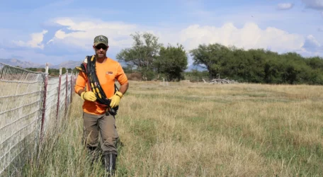 Field technician carrying geophysical cables across grassy terrain during soil characterization survey to evaluate subsurface soil variability, material contrasts, and site conditions for development and environmental planning.