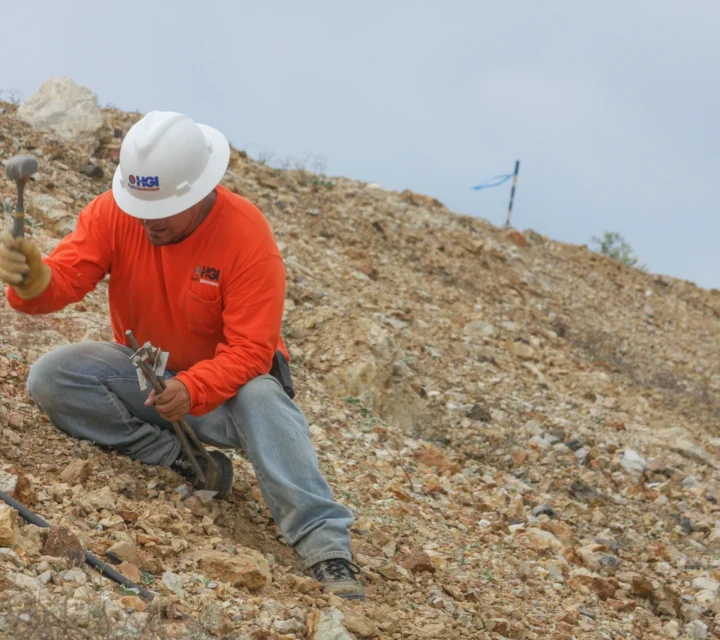 Field technician installing surface electrodes and testing equipment during soil characterization survey to measure subsurface resistivity and define soil layering, saturation levels, and site stability conditions.