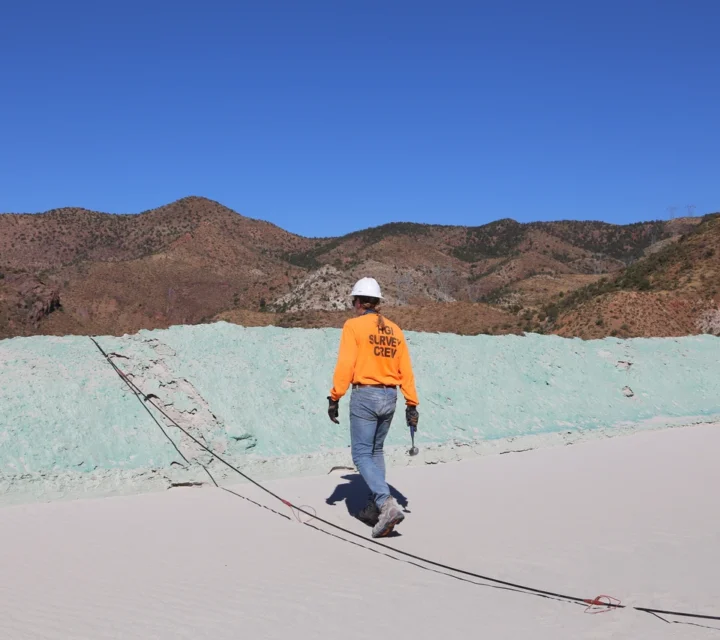 Technician walks across tailings facility deploying survey cables for Tailings dam characterization, mapping internal conditions, water-metal transport pathways, and structural variability to support long-term monitoring and management decisions.