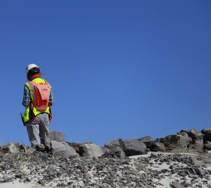 Technician surveys tailings embankment for Tailings dam characterization, mapping subsurface conditions, saturation distribution, and underlying rock strength to assess stability, contaminant pathways, and long-term containment performance.