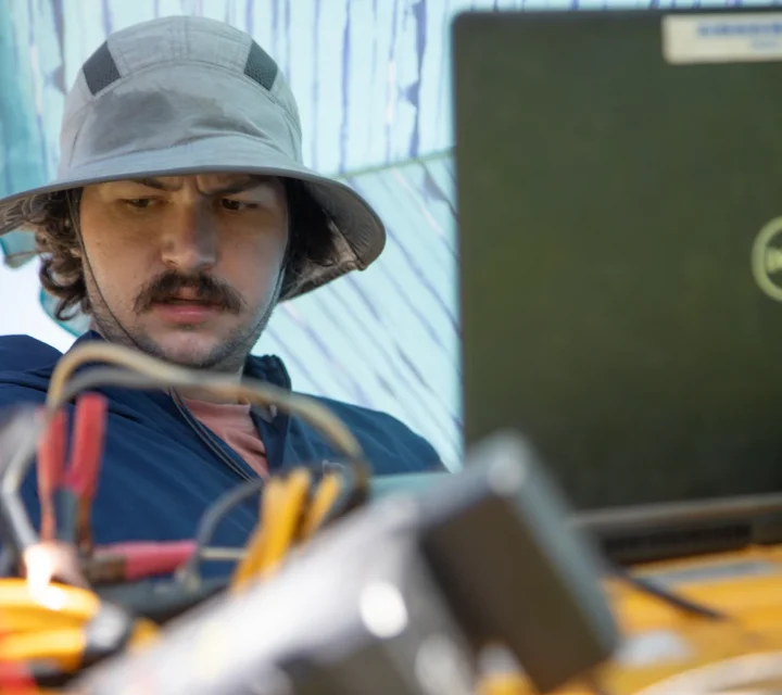 Geophysicist reviewing laptop data during void and karst detection survey, analyzing resistivity measurements to identify subsurface cavities, fractures, and dissolution features that increase geohazard and groundwater risk.